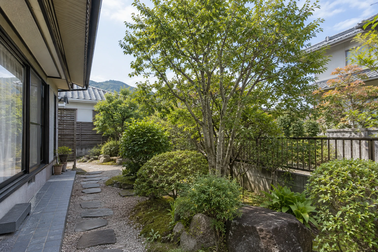 住宅の庭木と周囲の建物、通路
